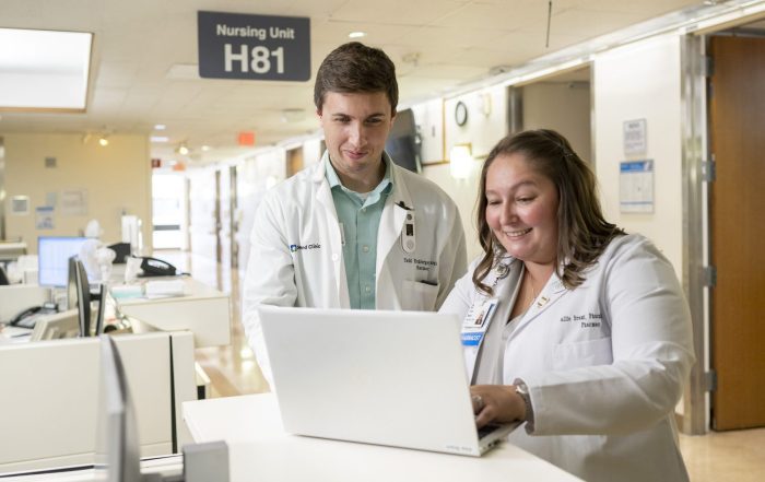Two caregivers working together on a computer in a Med/Surg unit.