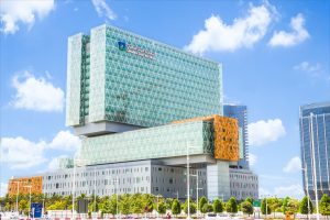 The modern glass exterior of Cleveland Clinic Abu Dhabi, featuring stacked geometric building sections under a clear sky.