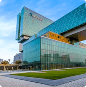 The modern glass exterior of Cleveland Clinic Abu Dhabi, featuring stacked geometric building sections under a clear sky.