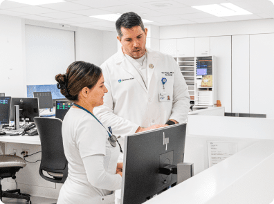 A Cleveland Clinic doctor and nurse review information on a computer screen together at a hospital workstation.