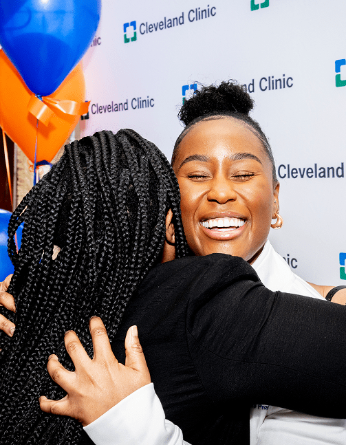 Close-up of a smiling female Cleveland Clinic caregiver hugging a fellow female caregiver